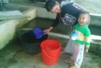 KETERANG GAMBAR :
Salah seorang ibu rumah tangga di kawasan jalan deliplantir terlihat sedang mengambil air hujan untuk kebutuhan dalam rumah tangganya. (Foto : Roy Prawira Pandia)