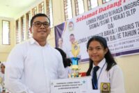 Pjs Bupati Toba, Dr Agustinus Panjaitan menyerahkan piala kepada Regina, Siswi SMP Budi Dharma Balige, juara 1 Lomba Pidato Berbahasa Inggris Tingkat SMP, se-Kecamatan Balige, Kabupaten Toba.