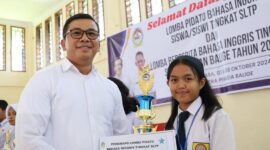 Pjs Bupati Toba, Dr Agustinus Panjaitan menyerahkan piala kepada Regina, Siswi SMP Budi Dharma Balige, juara 1 Lomba Pidato Berbahasa Inggris Tingkat SMP, se-Kecamatan Balige, Kabupaten Toba.
