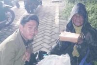 Ketua Pelaksana 'Program Mahasiswa Berbagi', Faza Pratama saat memberikan makanan kepada yang membutuhkan di area sekitar Indomaret Desa Medokan Ayu, Surabaya, Kamis (12/12/2024)