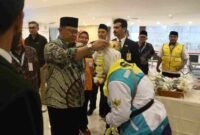 Prosesi simbolik pelepasan pun dilakukan dengan pengalungan bunga oleh Ketua PPIH kepada salah satu jamaah